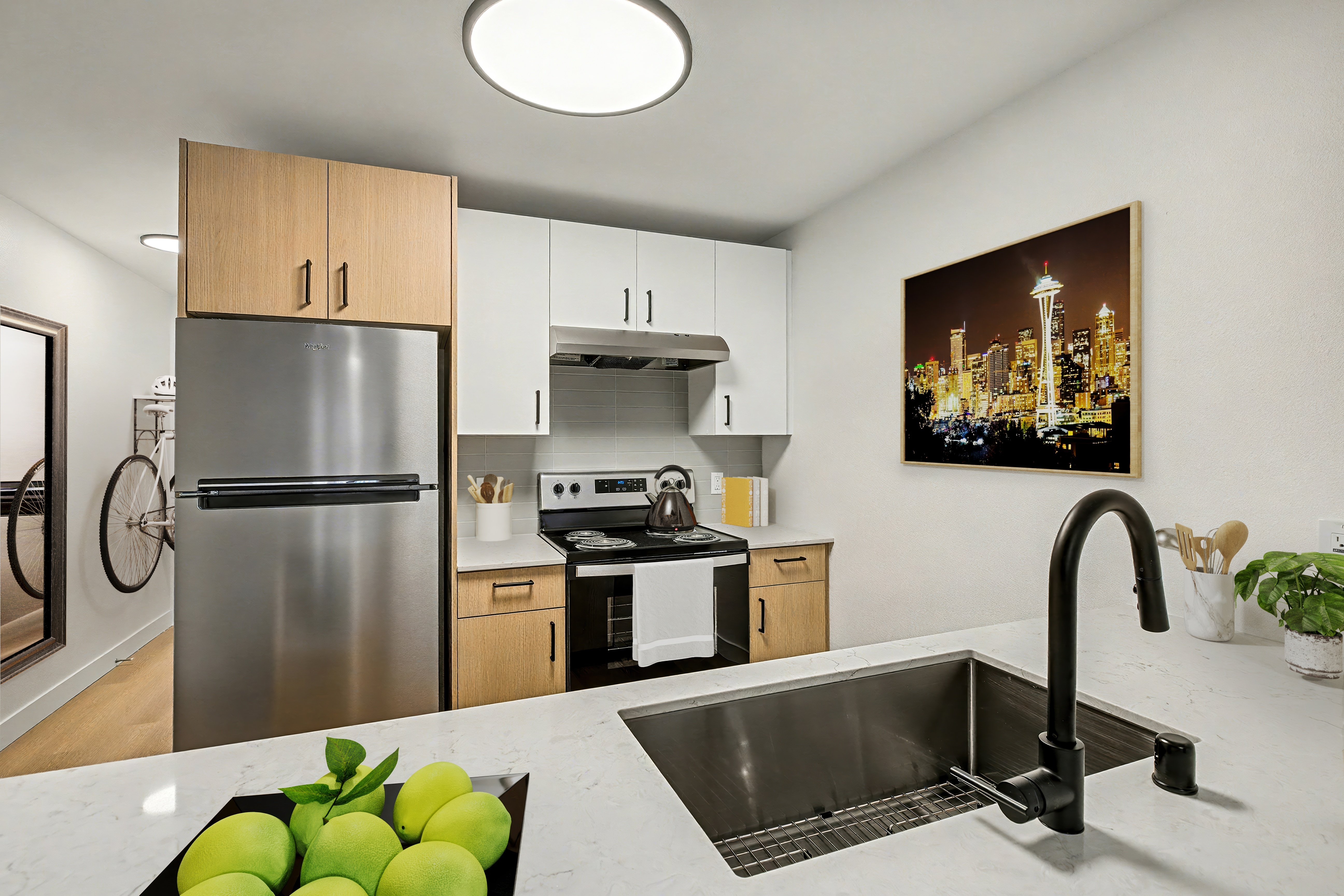 A kitchen with a refrigerator, sink, and a painting of a cityscape on the wall.